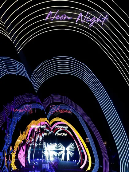 A tunnel of neon arches creates a futuristic and immersive entrance for guests, with words like 'Blessed' and 'Happiness' lighting the way into the 'Neon Night'.