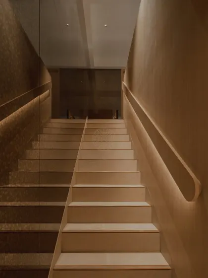 The staircase design is minimal yet impactful, with a mirrored wall on one side and integrated strip lighting under the handrail to create a warm, inviting glow.