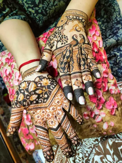 A creative design with one hand featuring peacocks under a tree and the other a floral vine pattern.