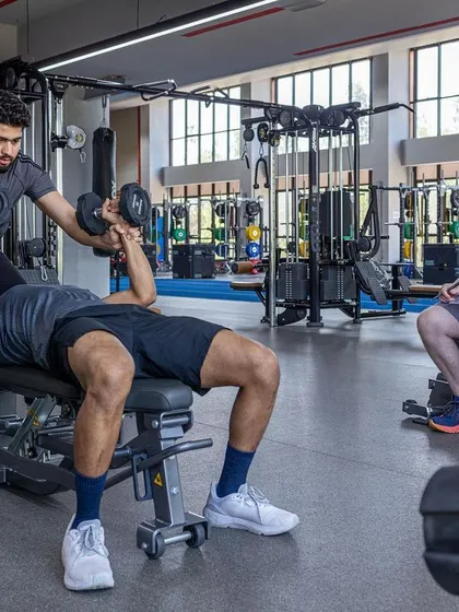 Hands-on coaching during a dumbbell bench press, ensuring safety and optimal technique for strength gains.