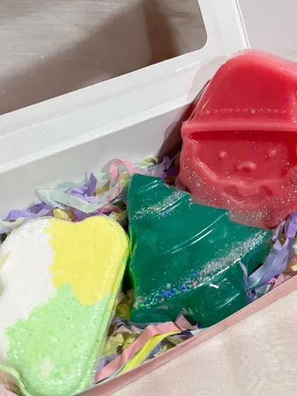 Our mini Christmas hamper is a fun and unique gift. This box contains a Santa-shaped soap, a Christmas tree soap, and a colorful bath bomb.