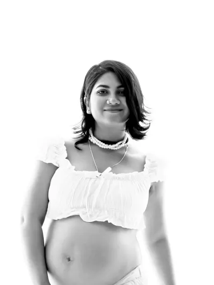 A simple and beautiful black and white portrait. The focus is entirely on the mother-to-be and her happy expression as she holds her baby bump.