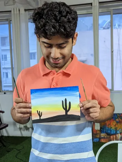 A participant with his watercolor painting of a desert scene at sunset.