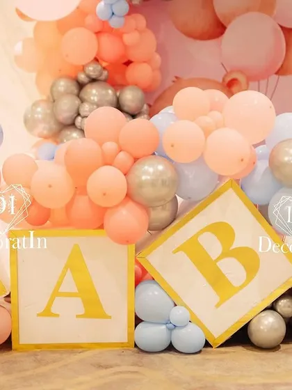 A close-up of the "BABY" blocks, surrounded by pink, blue, and silver balloons.