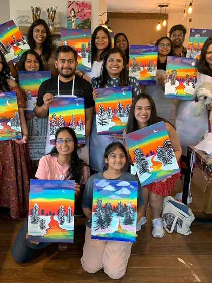 A group of friends proudly showing off their colorful landscape paintings. Our workshops are a great way to spend quality time with your favorite people.