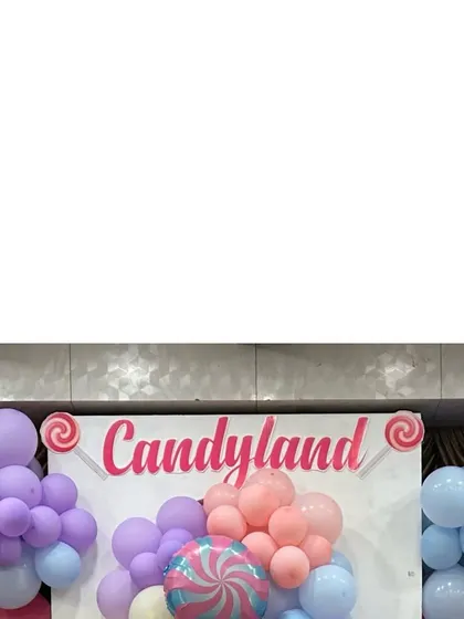 A "Candyland" sign surrounded by pastel-colored balloons, marking the theme of this sweet celebration.