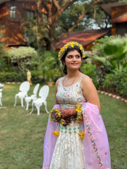 An outdoor shot of this beautiful Haldi look. The natural light highlights her glowing skin and the fresh, vibrant colors of her outfit and floral jewelry.
