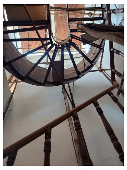 The curved metal hybrid staircase begins to take shape during construction, seen from below.