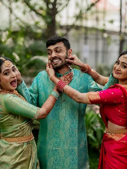 The groom surrounded by his sisters in a playful, candid moment. These family interactions add so much warmth and personality to the wedding album.