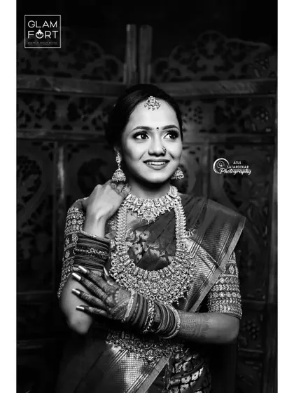 A timeless black and white portrait of a South Indian bride. This captures the elegance and grace of the moment, where the focus is on her joyful expression and the intricate details of her jewelry and makeup.