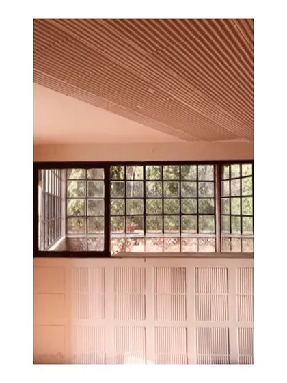 A detail from a farmhouse project emphasizing texture and light. The ribbed ceiling creates a dynamic play of shadows, while the gridded window frames the view of the surrounding nature, demonstrating how material choices can define a space.