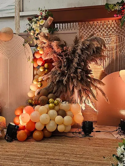 The main stage area for a boho-themed 30th birthday. The setup features arched backdrops, a large pampas grass arrangement, and a mix of balloons in earthy tones, creating a stunning focal point.