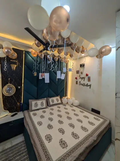 A full view of the decorated bedroom, showing balloons on the ceiling and scattered on the bed.