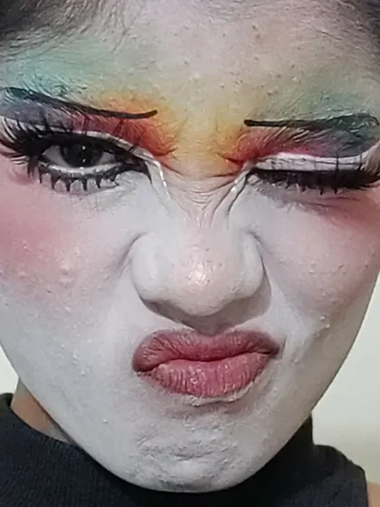 A close-up on the details of the clown makeup, including the textured white base and the blended rainbow colors.