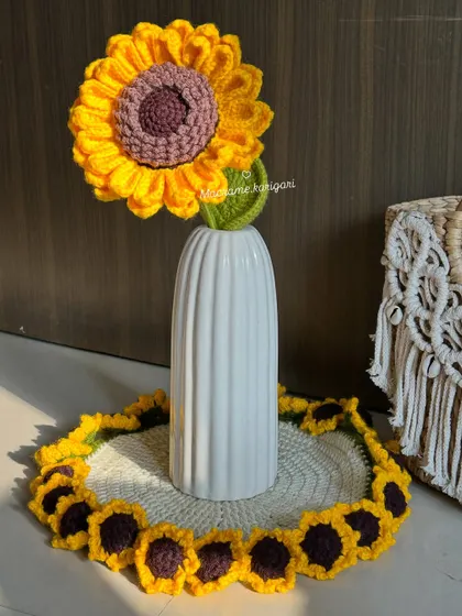 A single crochet sunflower stem placed in a vase on top of our sunflower table mat, creating a cohesive and sunny decorative theme.