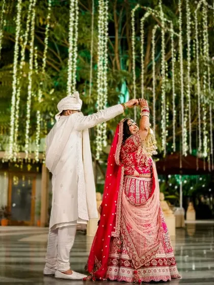 A beautiful dance under a canopy of cascading fairy lights. This wide shot captures the grandeur of the venue and the intimate moment between the couple, creating a feeling of romance and celebration.
