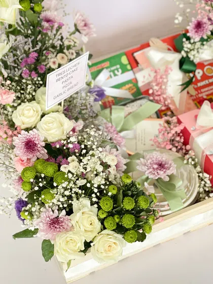 Another angle of the anniversary hamper, highlighting the fresh floral arrangements of roses and chrysanthemums that flank the edible gifts.