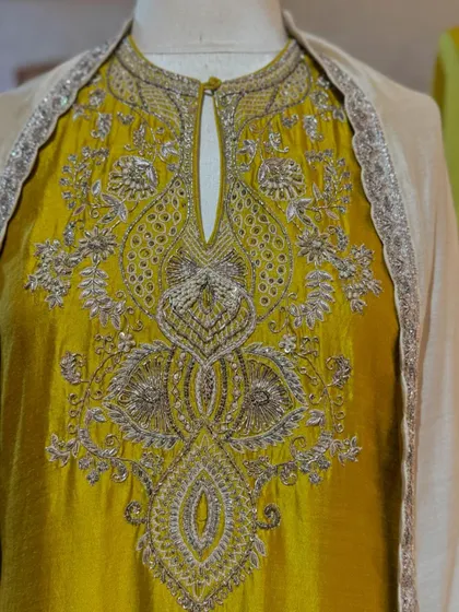A close-up of the incredibly detailed silver zardozi work on the yoke of a mustard yellow kurta.