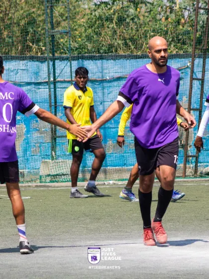 A player in a purple jersey receives a high-five from his teammate. Small moments of encouragement like this build morale and strengthen team bonds.