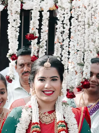 The bride's grand entrance, surrounded by smiling family and friends under a canopy of flowers.