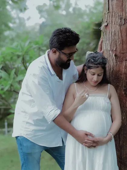 A gentle touch on the belly. This close-up shot emphasizes the protective and loving gesture of the father-to-be during their outdoor pregnancy photoshoot.