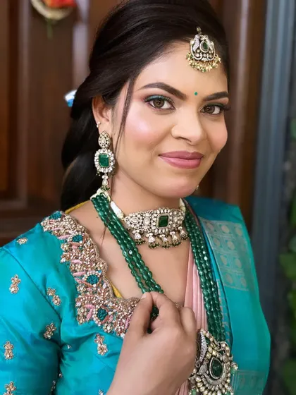 A stunning reception look with a pop of color. The turquoise and pink saree is complemented by makeup that features a hint of green eyeliner and a soft pink lip.