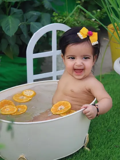 That smile is everything! She's having the best time in her little tub with orange slices on a warm day.