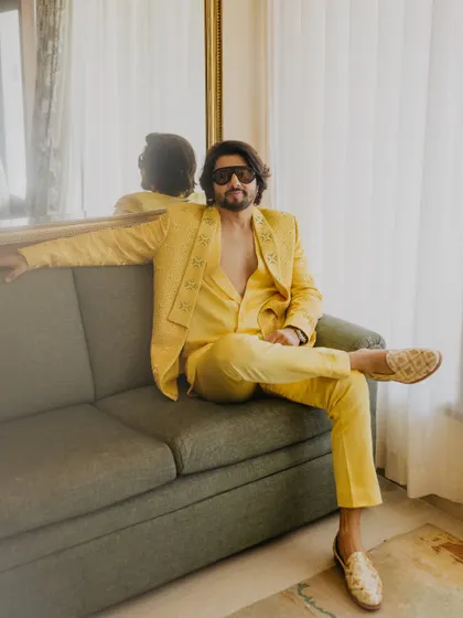 A stylish portrait of the groom relaxing on a sofa. His confident pose and fashionable yellow suit are captured in this modern and relaxed shot.