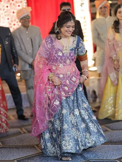 Our client enjoying a wedding celebration in a custom-designed blue printed lehenga, paired with a bright pink embroidered dupatta for a beautiful contrast.
