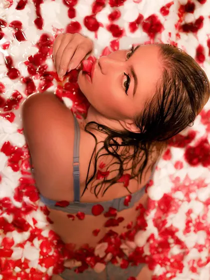 A creative milk bath shoot with rose petals. This overhead shot creates a beautiful, artistic composition, with the model surrounded by a sea of red and white.