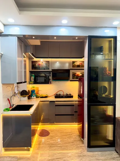 This compact kitchen uses clever lighting to feel bigger. We installed profile lighting under the lower cabinets and inside the glass display unit to create depth.