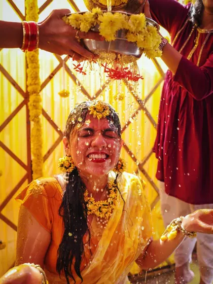A moment of pure bliss as the bride is showered with water and flowers during her Haldi.
