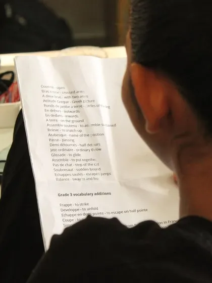 A student reviews her notes one last time. Preparation for ISTD exams involves not just physical practice but also learning the French terminology.
