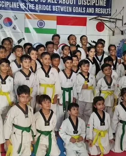 A large group photo of our students after a belt promotion ceremony, showcasing a wide range of belts from yellow to black.