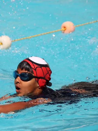 Here, a student in our swim camp practices his kicking technique using a kickboard. This drill is essential for building lower body strength and proper form.