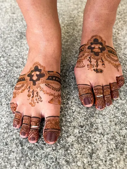 An intricate baby shower themed leg mehendi, with delicate patterns that look like jewelry on the feet.