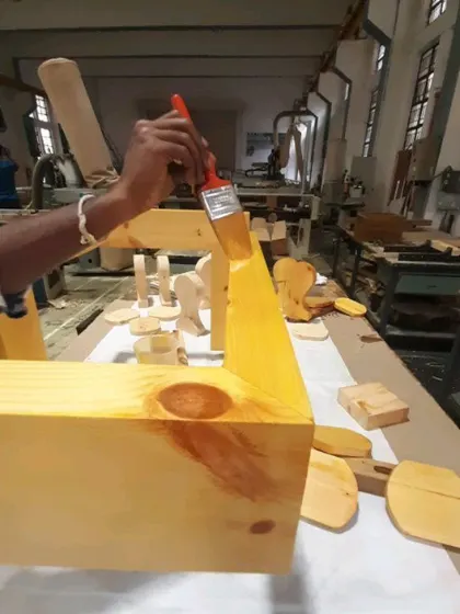 A student applies a coat of finish to a project, the final step in protecting the wood and bringing out its natural beauty.