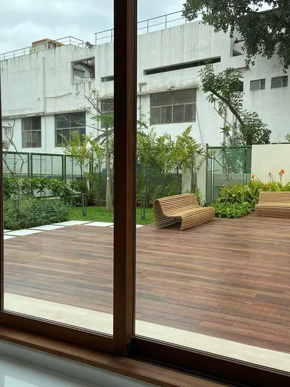 A view from inside looking out onto the spacious wooden deck and garden. We design outdoor spaces that serve as a true extension of the home, perfect for relaxation or entertaining.
