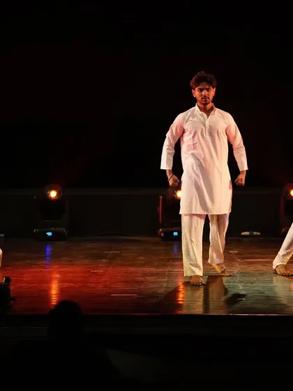 The three lead dancers of 'Inquilab' in a moment of intense, synchronized movement.