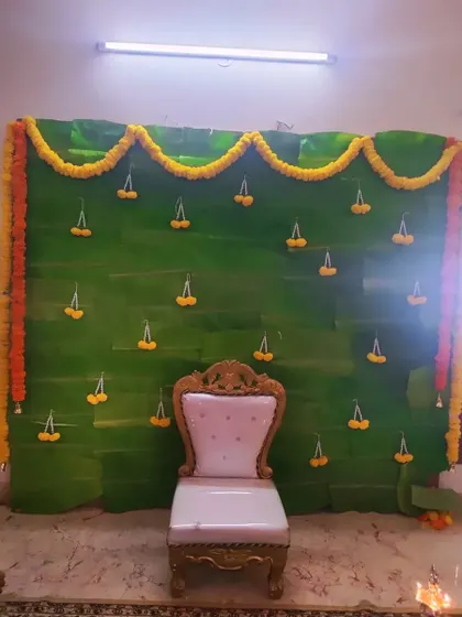 Another view of the banana leaf backdrop, this time with a chair placed for seating. It's a versatile setup for various traditional functions.