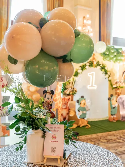 A themed table centerpiece with a balloon bouquet and a small Mickey cutout, bringing the jungle theme to every table.