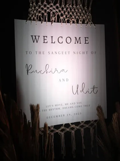 A chic welcome sign for the Sangeet night, featuring modern calligraphy and macrame details that align with the event's boho-glam theme.