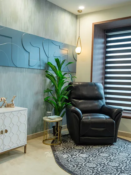 A cozy reading corner within the study room, featuring a plush black leather recliner, a gold-accented side table, and a unique 3D textured wall panel. This corner is perfect for unwinding after a productive day.