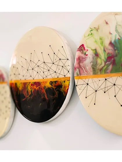 Nature's beauty flows through this installed resin artwork. This triptych combines fluid paint pours with geometric line drawings, creating a balance between organic and structured design.