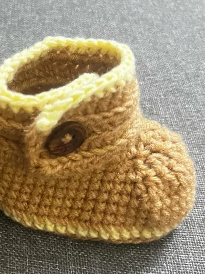 This is one of the adjustable baby booties, showing the soft texture and the neat stitching. They are designed to be both comfortable and durable for active little ones.