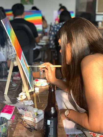 A close-up of a painter working on a vibrant, colorful landscape. The focus and dedication are real, but so is the fun.