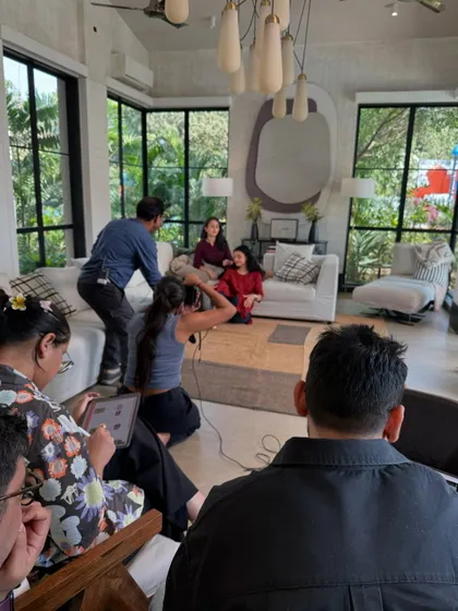 A wide shot of the team at work during an indoor shoot. It shows the collaborative effort involved, with stylists, assistants, and co-photographers all focused on creating the final image.