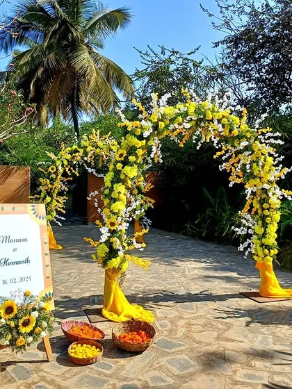A sunny and cheerful entrance arch made of yellow flowers and sunflowers for a daytime event.