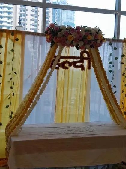A swing-style seating arrangement for a Haldi ceremony, decorated with floral strings and a dreamcatcher. This setup is ideal for apartment balconies or smaller indoor spaces.
