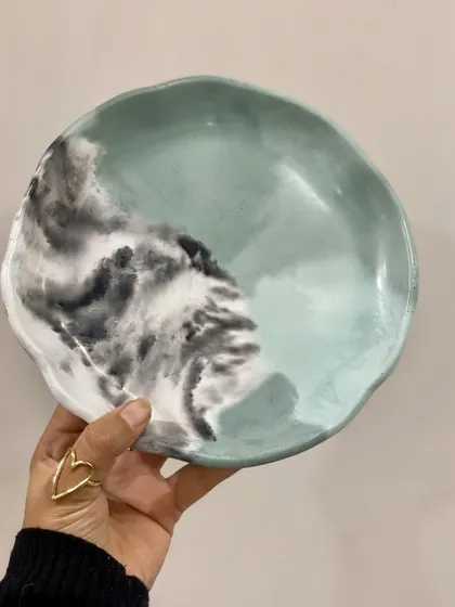 Holding up the live-edge tray to show its unique, hand-casted form and the beautiful blend of mint green and grey.